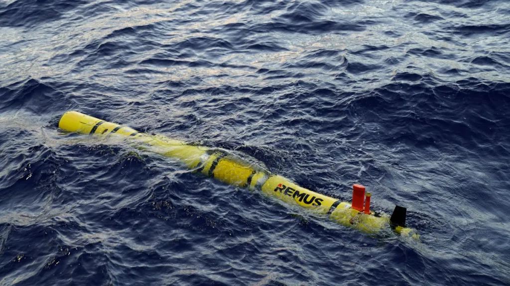 UN vehículo A REMUS 600 de color amarillo parcialmente sumergido en el mar. 